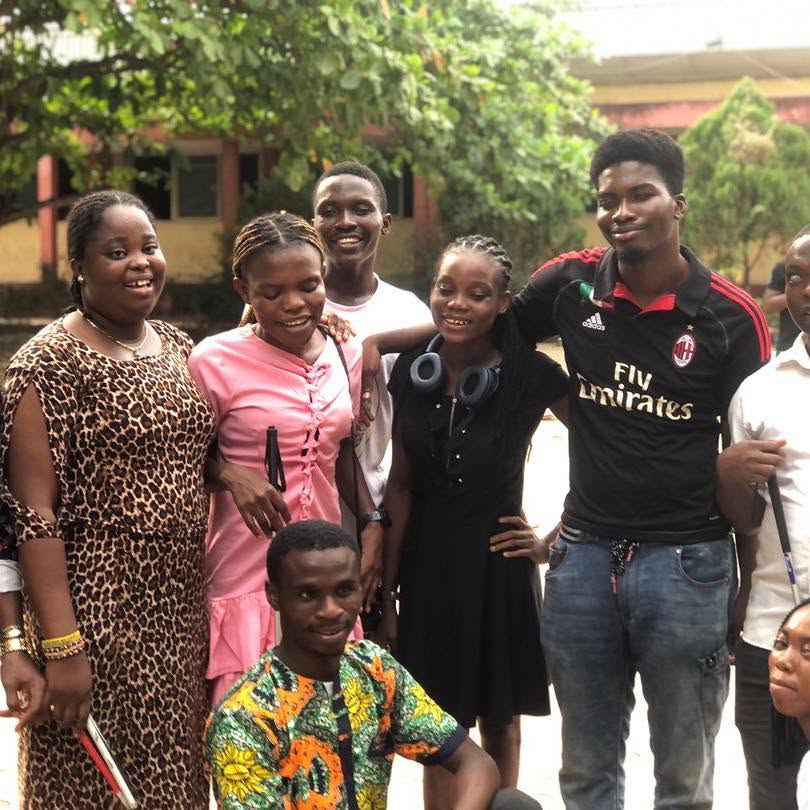 Members of the visually impaired student community, several holding white canes, gathered together outdoors.